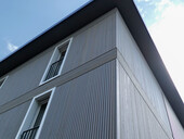 Das elegante vertikale Profil der Holzfassade setzt den Bau in Szene